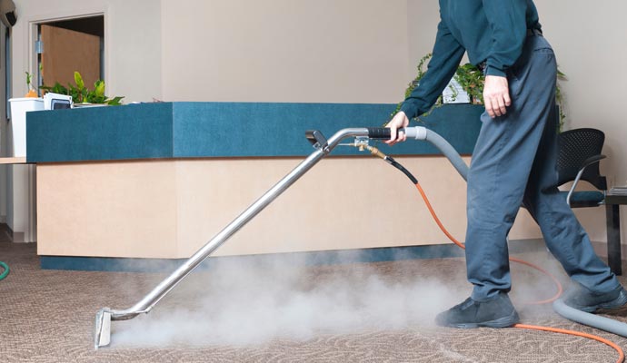 Professional worker cleaning carpet in a commercial space