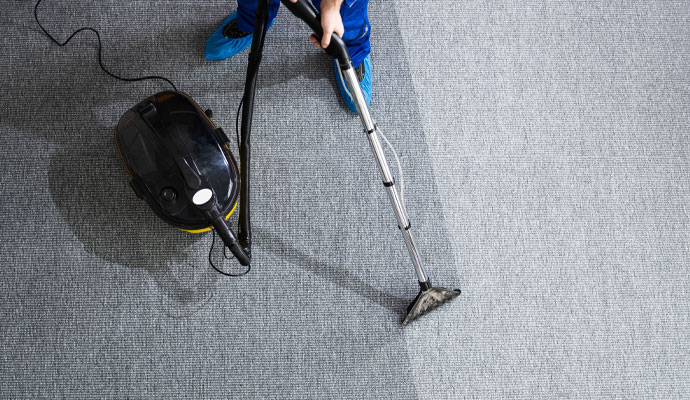 Technician using steam extraction wand for commercial carpet deep cleaning