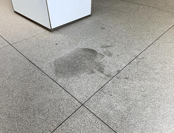 Commercial granite floor surface showing visible stain and discoloration on polished stone flooring