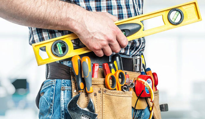 Commercial handyman wearing tool belt and holding spirit level