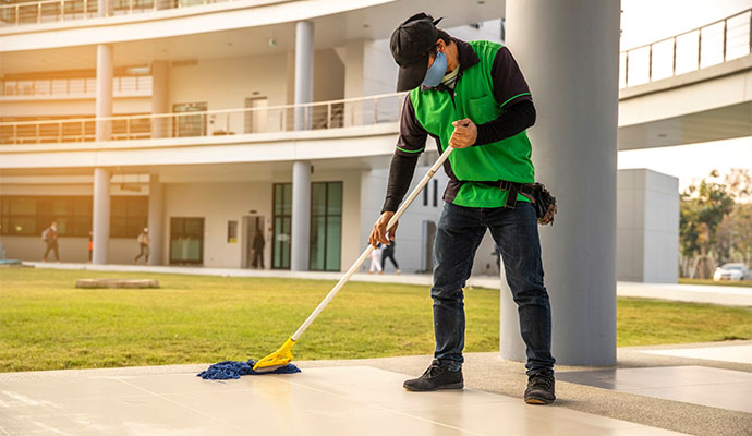 A janitor mopping a floor with a wet floor sign