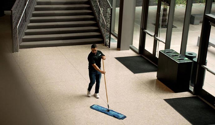 Professional janitorial staff cleaning commercial lobby flooring inside modern office building entrance area