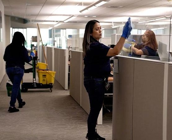 Professional janitorial staff cleaning and disinfecting modern commercial office workspace and cubicle areas