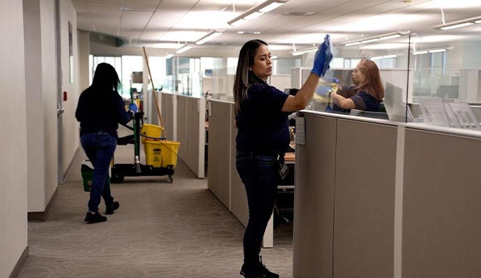 Professional janitorial staff cleaning and disinfecting modern commercial office workspace and cubicle areas