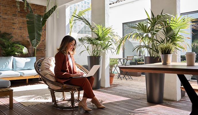 A woman working on a laptop in a bright, modern outdoor patio office