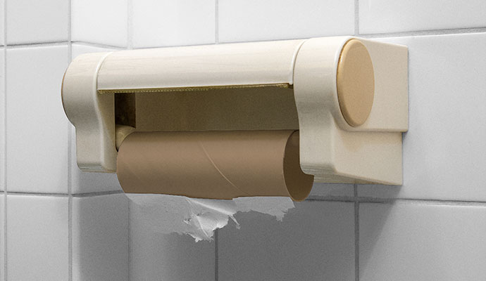 Empty toilet paper cardboard tube on wall-mounted restroom dispenser