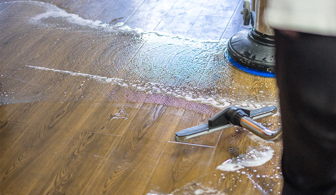 Floor scrubber machine and extraction wand cleaning an engineered wood floor