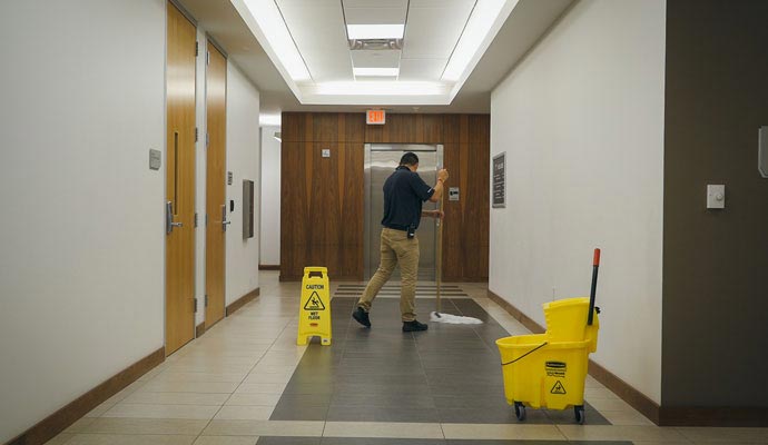 An expert cleaning the floor in a hallway near an elevator