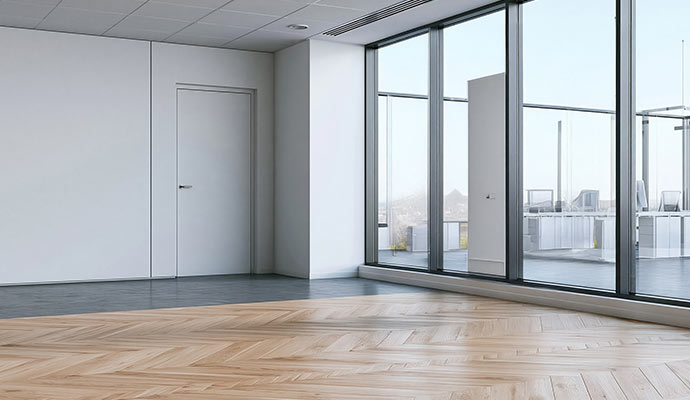 Commercial office room with herringbone engineered wood flooring and large windows