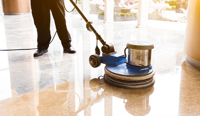 Professional machine cleaning and maintaining polished marble flooring inside commercial building lobby