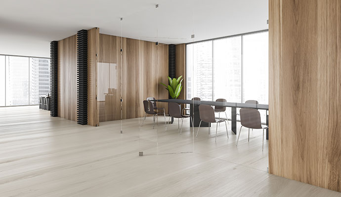 A modern and clean office conference room with a large table and chairs, surrounded by glass and light wood walls, and large windows with a city view