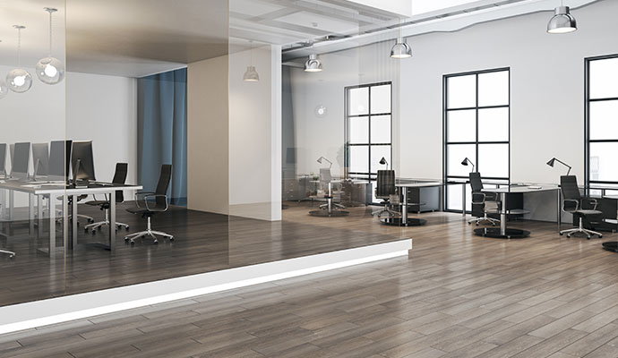 A wide shot of a clean, modern, two-level office space with computers on desks, a glass partition, and large windows