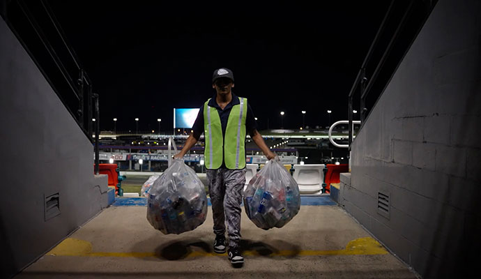 A cleaner removing trash after an event by carrying two large garbage bags