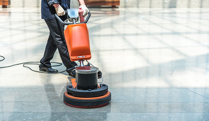 Technician cleaning tile floor with machine