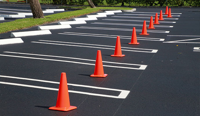 Freshly striped commercial parking lot with crisp white stall lines and safety cones