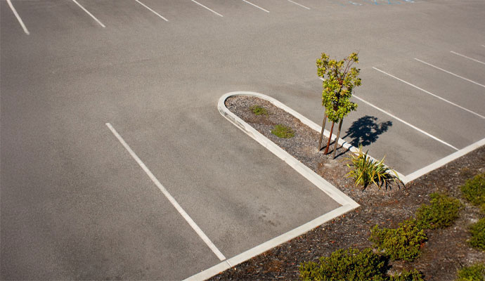 An aerial view of a clean and well-maintained asphalt parking lot with freshly painted white lines and landscaped islands
