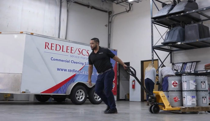 A stock worker moves supplies on a pallet in a warehouse or industrial space