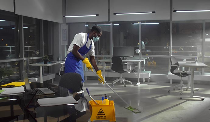 Expert cleaning the floor in a modern office at night