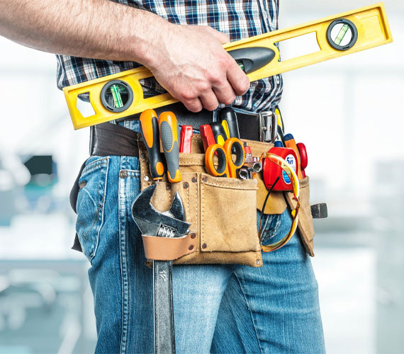 A professional handyman or contractor with a leather tool belt and a yellow level in his hand, ready to work