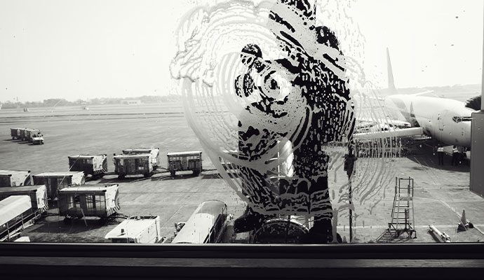 Janitorial staff cleaning outside window at airport