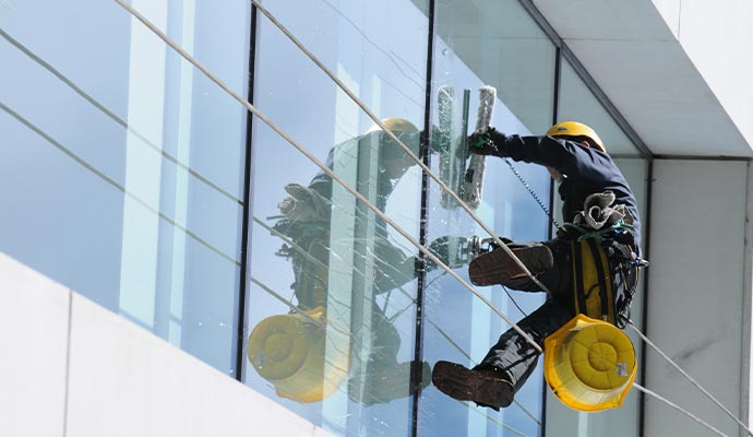 Expert performing exterior window cleaning on a high-rise commercial building