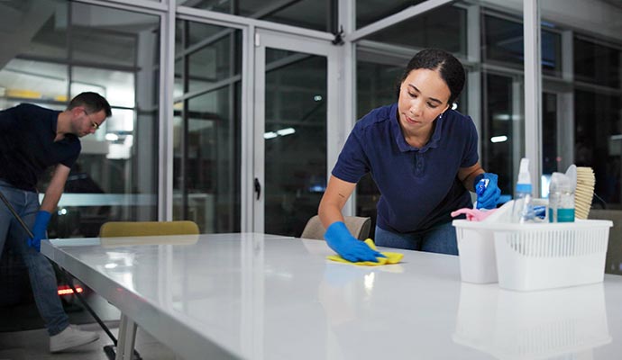 Two experts cleaning the desk and floor in an office