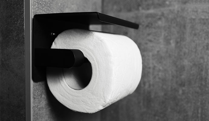 Modern black wall-mounted toilet paper dispenser with shelf in commercial restroom