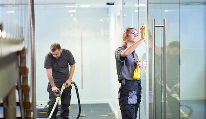 Two professional cleaners working in an office.