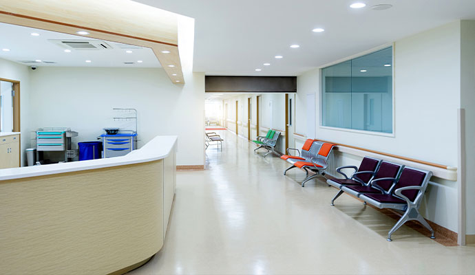 The interior of a modern healthcare facility hallway with clean floors and walls, leading to patient rooms