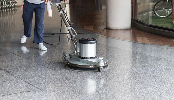 Worker polishing smooth commercial concrete and terrazzo floor with rotary machine