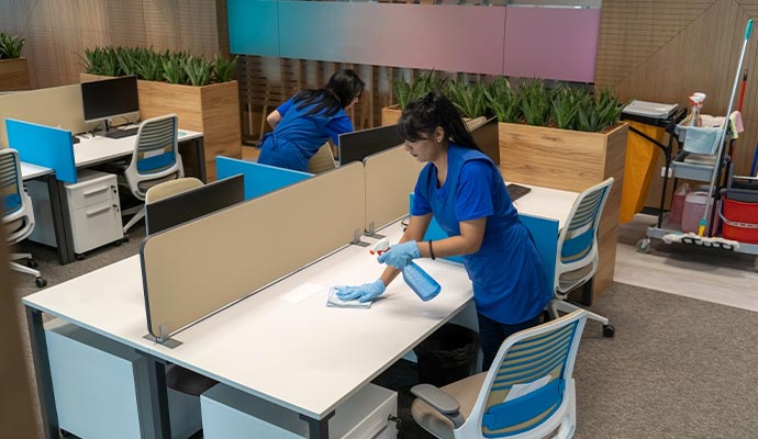 Professional cleaning team disinfecting desks in modern office