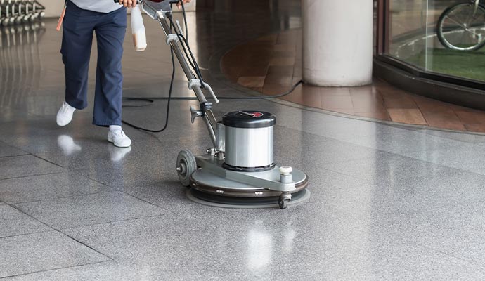 Professional technician using floor machine to clean and maintain commercial granite flooring surface
