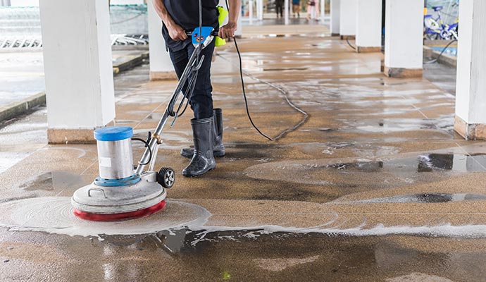 Professional technician using floor machine to deep clean commercial hard surface flooring outdoors