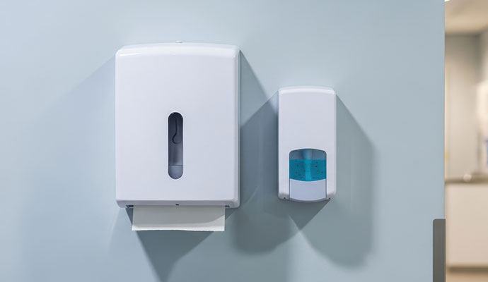 Wall-mounted paper towel and hand soap dispensers in commercial restroom