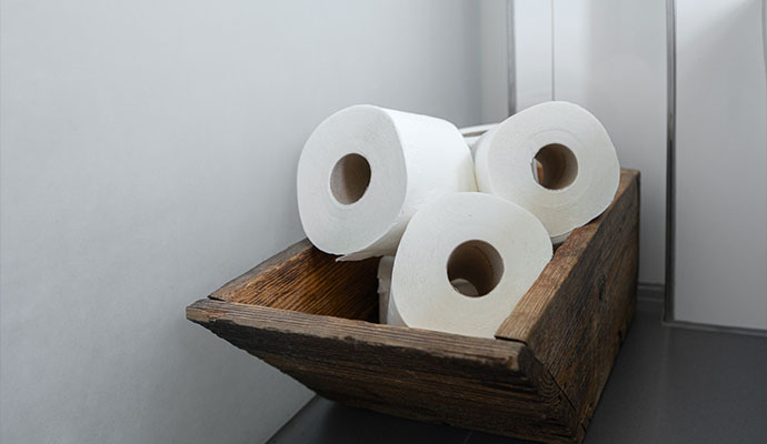 Extra rolls of toilet paper stored in a wooden container in restroom