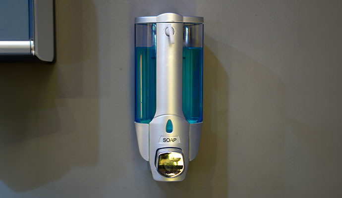 Wall-mounted commercial liquid soap dispenser filled with blue hand soap
